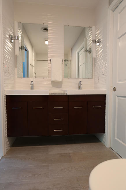Modern inredning av ett litet badrum, med ett fristående handfat, släta luckor, skåp i mörkt trä, marmorbänkskiva, ett badkar i en alkov, en dusch/badkar-kombination, en toalettstol med hel cisternkåpa, vit kakel, porslinskakel, vita väggar, klinkergolv i porslin och grått golv