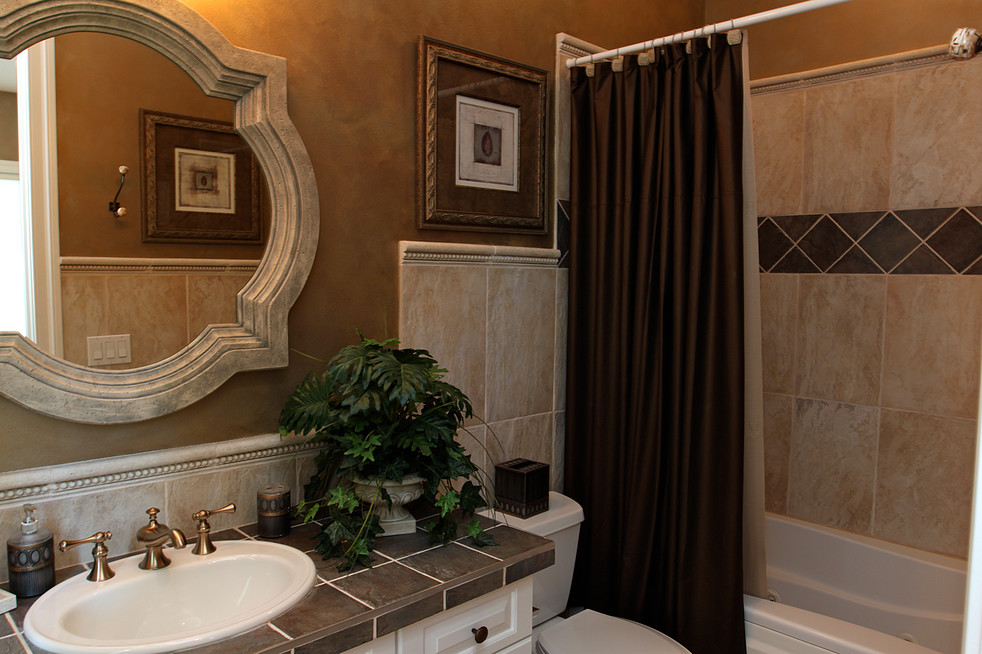 Пример оригинального дизайна: большая главная ванная комната в стиле неоклассика (современная классика) с накладной раковиной, фасадами с выступающей филенкой, белыми фасадами, столешницей из плитки, ванной в нише, душем над ванной, раздельным унитазом, серой плиткой, керамической плиткой, коричневыми стенами и полом из керамогранита