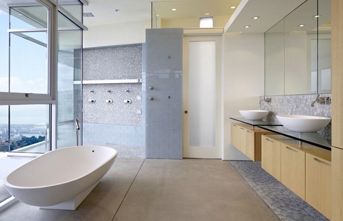 Foto på ett mellanstort funkis en-suite badrum, med ett fristående handfat, möbel-liknande, skåp i ljust trä, bänkskiva i glas, ett fristående badkar, en öppen dusch, en vägghängd toalettstol, grå kakel, glaskakel, vita väggar och betonggolv