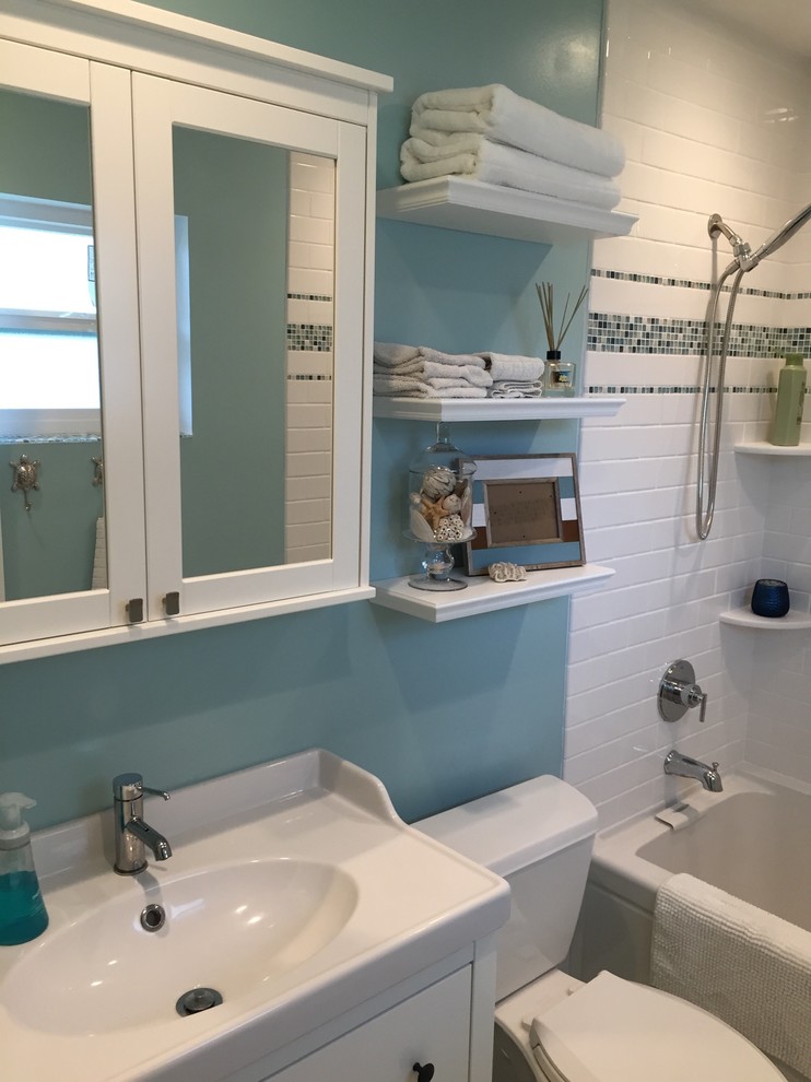 Свежая идея для дизайна: главная ванная комната среднего размера в морском стиле с плоскими фасадами, черными фасадами, ванной в нише, душем над ванной, унитазом-моноблоком, белой плиткой, плиткой кабанчик, синими стенами, полом из керамогранита, монолитной раковиной, столешницей из искусственного кварца, серым полом, шторкой для ванной и белой столешницей - отличное фото интерьера