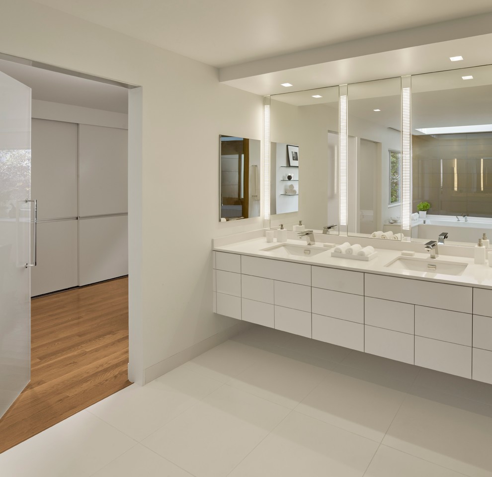 Пример оригинального дизайна: большая главная ванная комната в современном стиле с плоскими фасадами, белыми фасадами, ванной в нише, белыми стенами, полом из керамогранита, врезной раковиной, столешницей из искусственного камня и белой столешницей