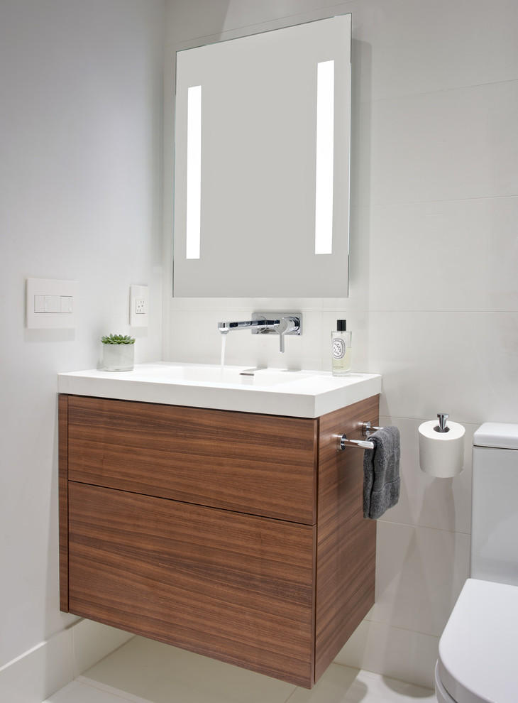 Inspiration for a small modern ensuite bathroom in San Francisco with flat-panel cabinets, dark wood cabinets, an alcove bath, a shower/bath combination, a one-piece toilet, white tiles, ceramic tiles, white walls, ceramic flooring, an integrated sink, engineered stone worktops, white floors, a hinged door and white worktops.