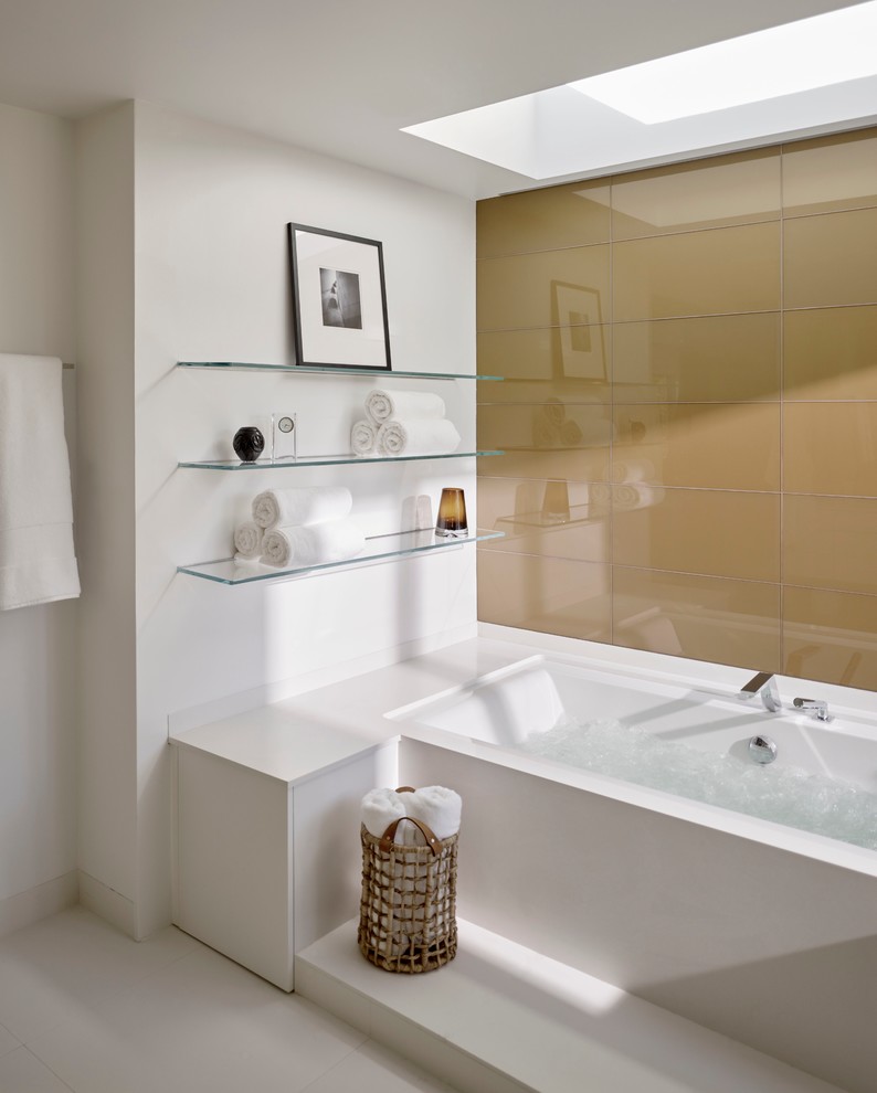 This is an example of a large contemporary ensuite bathroom in San Francisco with flat-panel cabinets, white cabinets, an alcove bath, white tiles, stone slabs, white walls, porcelain flooring, a submerged sink and solid surface worktops.