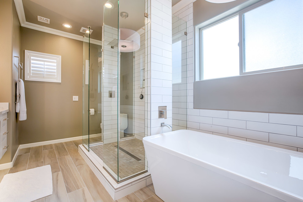 Modern inredning av ett stort en-suite badrum, med släta luckor, vita skåp, ett fristående badkar, en öppen dusch, en toalettstol med hel cisternkåpa, vit kakel, tunnelbanekakel, grå väggar, klinkergolv i porslin, ett undermonterad handfat, bänkskiva i kvartsit, grått golv och med dusch som är öppen