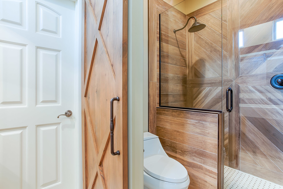 Lantlig inredning av ett mellanstort badrum med dusch, med luckor med upphöjd panel, skåp i mellenmörkt trä, ett badkar i en alkov, en dusch i en alkov, en toalettstol med hel cisternkåpa, brun kakel, porslinskakel, beige väggar, marmorgolv, ett avlångt handfat, granitbänkskiva, vitt golv och med dusch som är öppen