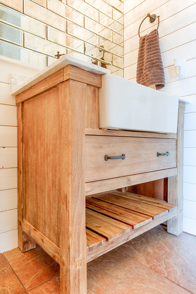 Inspiration för små lantliga badrum, med skåp i mellenmörkt trä, en toalettstol med hel cisternkåpa, brun kakel, vita väggar, klinkergolv i porslin, ett avlångt handfat, marmorbänkskiva och beiget golv