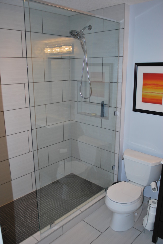 Small modern shower room bathroom in Calgary with shaker cabinets, dark wood cabinets, an alcove shower, a two-piece toilet, beige tiles, porcelain tiles, beige walls, laminate floors, a submerged sink, solid surface worktops, beige floors and a hinged door.