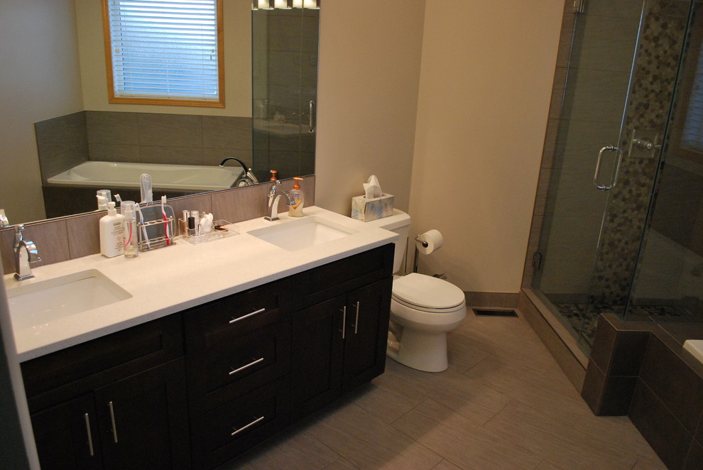 Design ideas for a medium sized traditional ensuite bathroom in Calgary with shaker cabinets, dark wood cabinets, a built-in bath, a corner shower, a two-piece toilet, multi-coloured tiles, pebble tiles, beige walls, laminate floors, a submerged sink, solid surface worktops, beige floors and a hinged door.