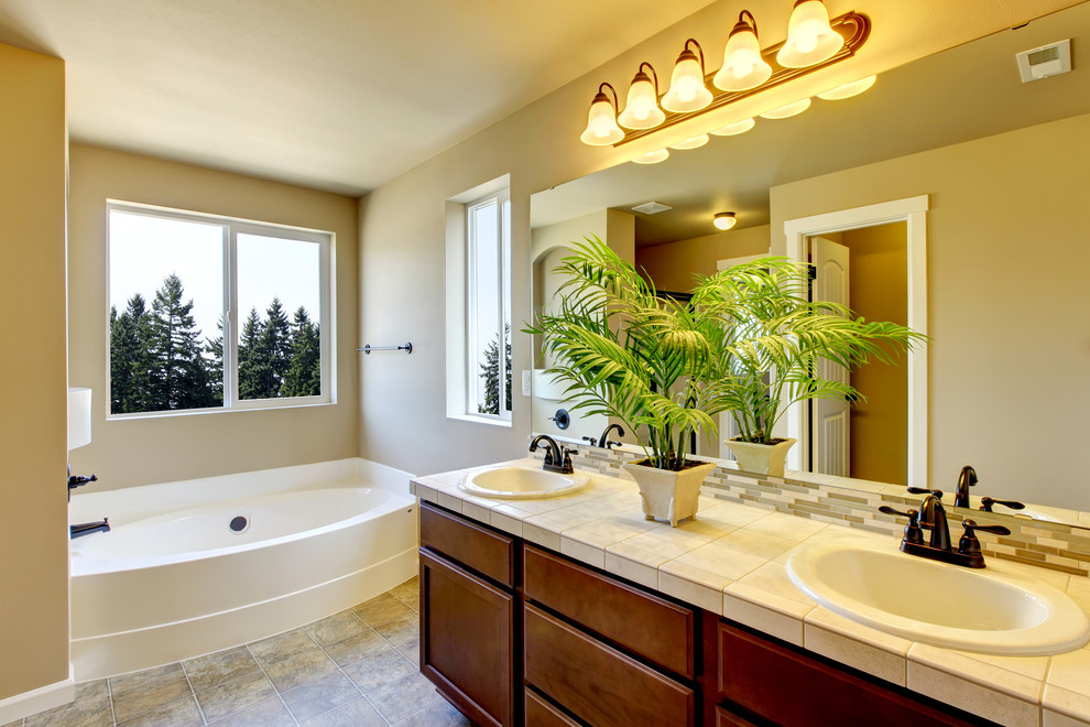 Photo of a medium sized classic ensuite bathroom in DC Metro with a built-in sink, flat-panel cabinets, medium wood cabinets, tiled worktops, an alcove bath, a one-piece toilet, beige tiles and beige walls.