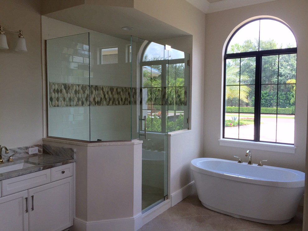 Klassisk inredning av ett mellanstort en-suite badrum, med skåp i shakerstil, vita skåp, granitbänkskiva, ett fristående badkar, vit kakel, keramikplattor, beige väggar och klinkergolv i porslin