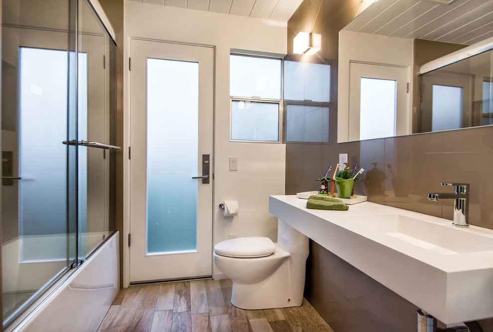 Contemporary bathroom in San Francisco with an integrated sink, an alcove bath, a shower/bath combination, a one-piece toilet and beige tiles.