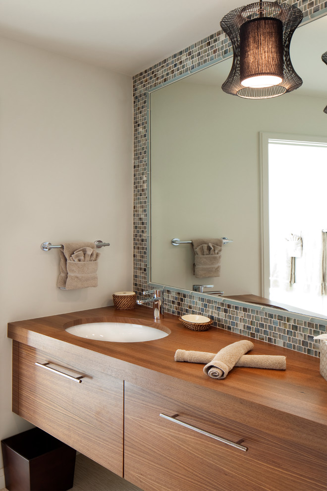 Idee per una stanza da bagno minimal con lavabo sottopiano, ante lisce, ante in legno scuro, top in legno, piastrelle multicolore e pareti bianche