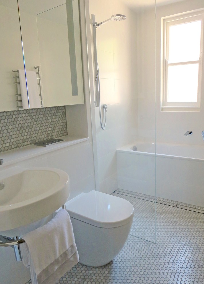 На фото: ванная комната среднего размера в современном стиле с фасадами с выступающей филенкой, ванной в нише, открытым душем, унитазом-моноблоком, белой плиткой, керамической плиткой, полом из керамической плитки, подвесной раковиной, серым полом и открытым душем