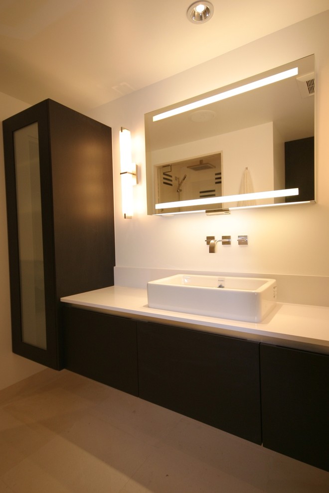Foto di una stanza da bagno con doccia moderna di medie dimensioni con ante lisce, ante nere, pareti bianche, pavimento in pietra calcarea, lavabo a bacinella e top in superficie solida