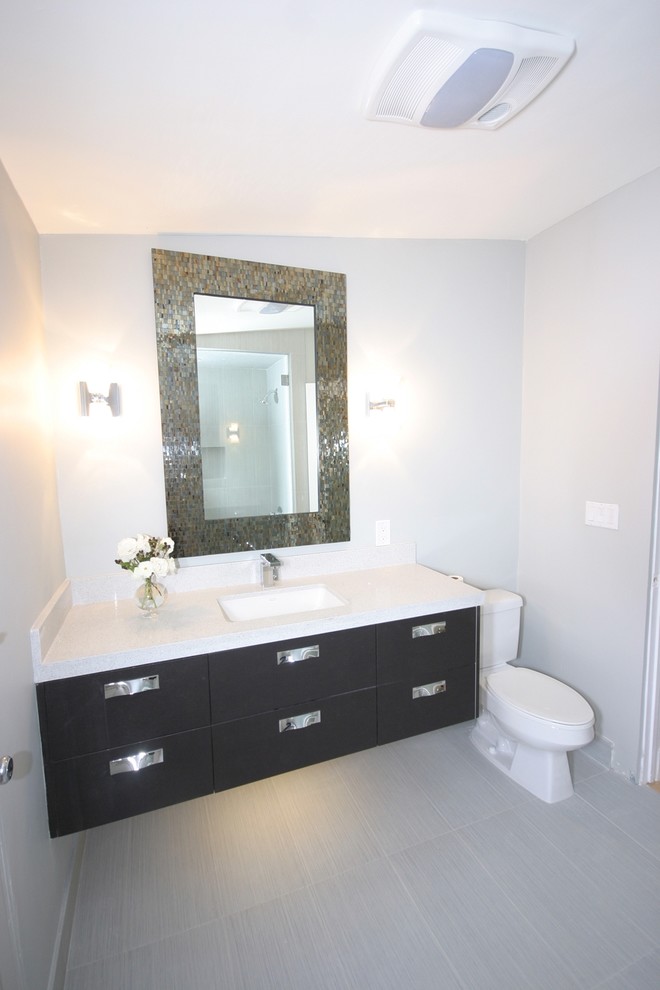 Idéer för att renovera ett mellanstort funkis badrum med dusch, med släta luckor, svarta skåp, en toalettstol med separat cisternkåpa, grå kakel, porslinskakel, vita väggar, klinkergolv i porslin, ett undermonterad handfat och marmorbänkskiva