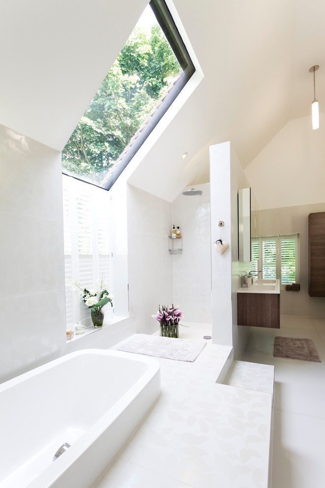 This is an example of a large contemporary ensuite half tiled bathroom in Oxfordshire with a wall-mounted sink, a built-in bath, a walk-in shower, white tiles, white walls, a wall mounted toilet, porcelain tiles, porcelain flooring and an open shower.