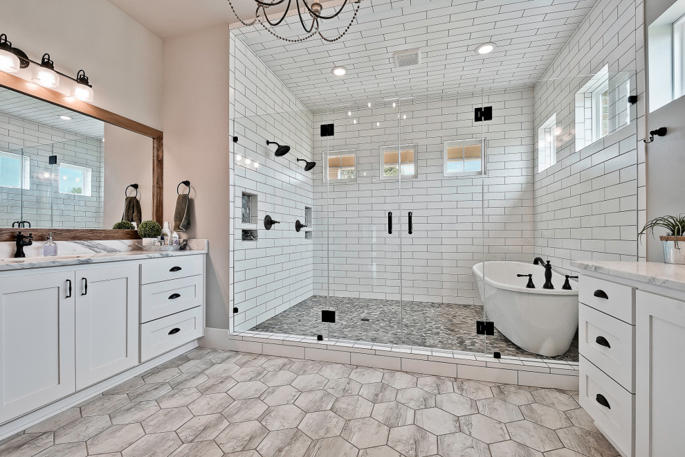 Lantlig inredning av ett stort grå grått en-suite badrum, med släta luckor, vita skåp, ett fristående badkar, en öppen dusch, en toalettstol med separat cisternkåpa, vit kakel, porslinskakel, grå väggar, klinkergolv i porslin, ett undermonterad handfat, bänkskiva i kvartsit, grått golv och dusch med gångjärnsdörr