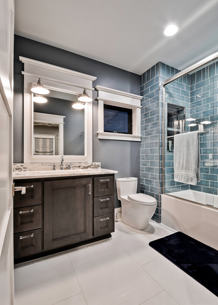 Cette image montre une grande salle de bain traditionnelle en bois foncé pour enfant avec un placard avec porte à panneau encastré, un mur bleu, un sol en carrelage de porcelaine, un lavabo encastré, un plan de toilette en quartz, un sol gris, un plan de toilette beige, meuble simple vasque, meuble-lavabo encastré, une baignoire en alcôve, un combiné douche/baignoire, WC à poser, un carrelage bleu et une cabine de douche à porte coulissante.