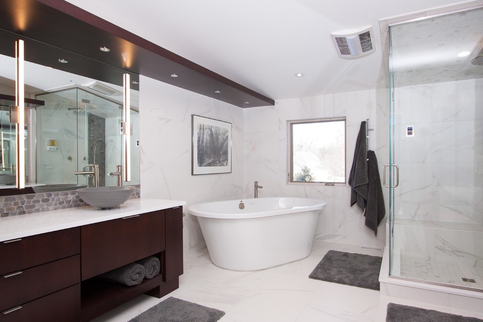 На фото: большая главная ванная комната в современном стиле с плоскими фасадами, темными деревянными фасадами, отдельно стоящей ванной, угловым душем, каменной плиткой, белыми стенами, мраморным полом, настольной раковиной и столешницей из искусственного камня с