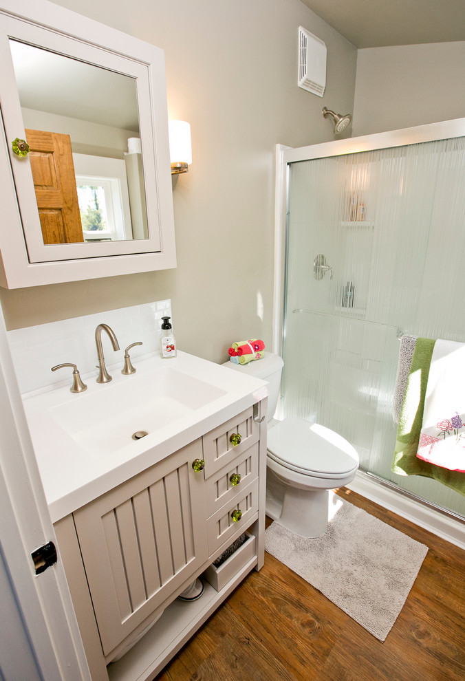 Imagen de cuarto de baño campestre pequeño con lavabo integrado, puertas de armario grises, encimera de acrílico, paredes grises, aseo y ducha y armarios con paneles empotrados