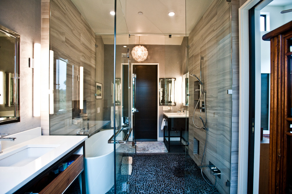 Idéer för ett mellanstort modernt vit en-suite badrum, med släta luckor, skåp i mörkt trä, ett fristående badkar, våtrum, en vägghängd toalettstol, grå kakel, marmorkakel, grå väggar, betonggolv, ett undermonterad handfat, bänkskiva i kvarts, grått golv och dusch med gångjärnsdörr