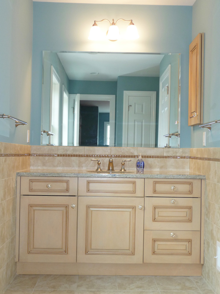 На фото: ванная комната в классическом стиле с врезной раковиной, фасадами с выступающей филенкой, светлыми деревянными фасадами, столешницей из гранита и коричневой плиткой с