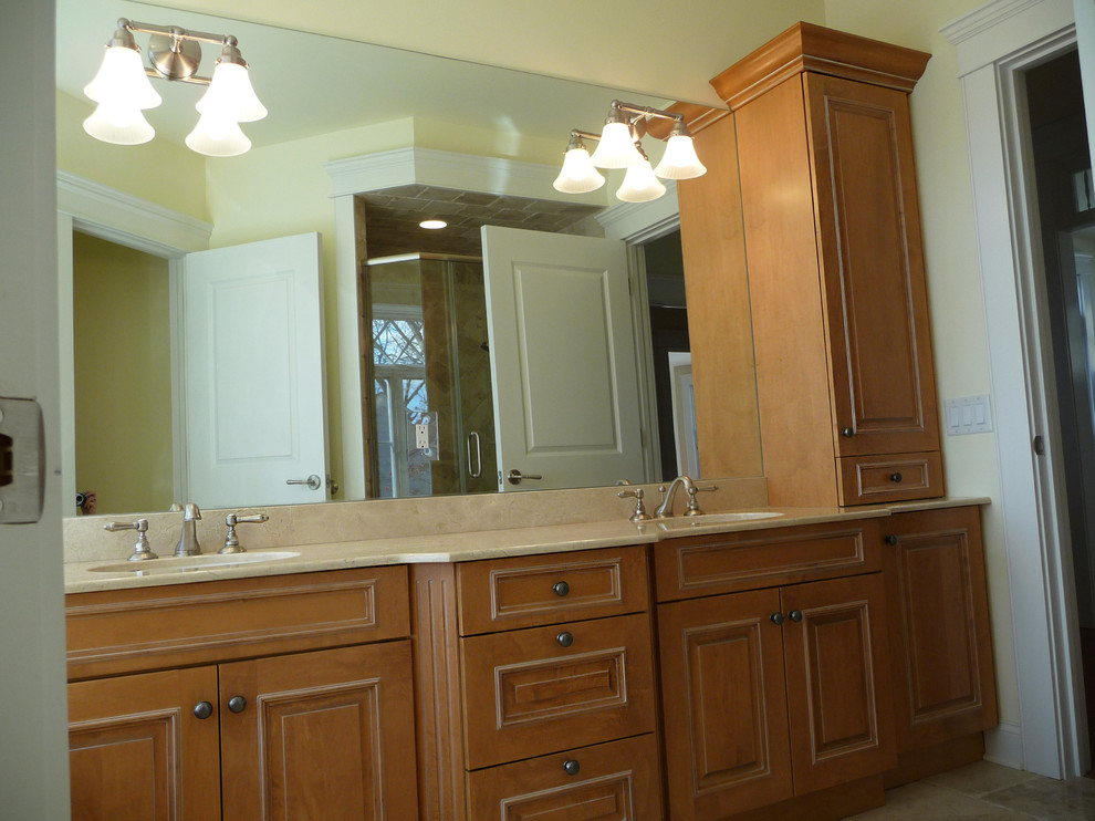Imagen de cuarto de baño tradicional con lavabo bajoencimera, armarios con paneles con relieve, puertas de armario de madera clara y encimera de mármol