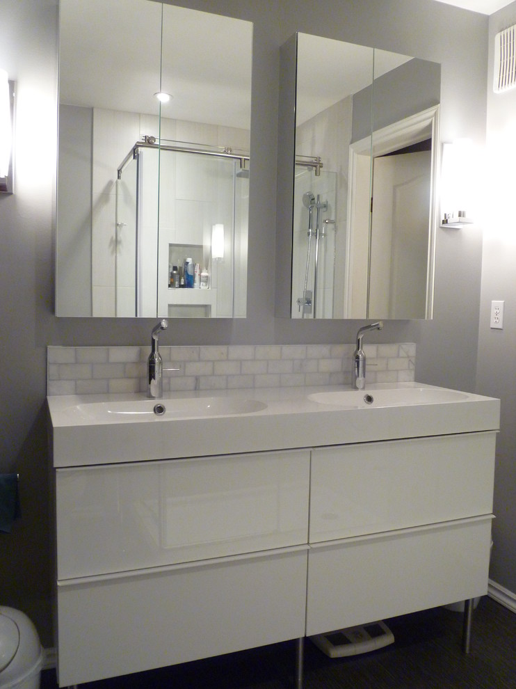 Small modern ensuite bathroom in Edmonton with flat-panel cabinets, white cabinets, a corner shower, a one-piece toilet, white tiles, marble tiles, grey walls, limestone flooring, an integrated sink, solid surface worktops, grey floors and a sliding door.