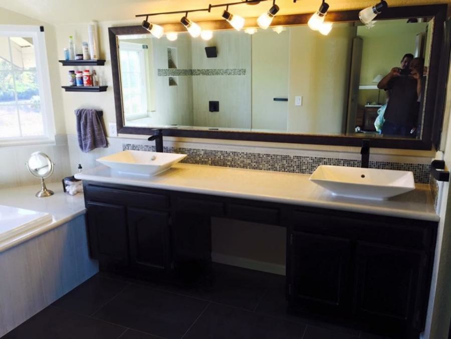 На фото: главная ванная комната среднего размера в стиле неоклассика (современная классика) с плоскими фасадами, темными деревянными фасадами, накладной ванной, черной плиткой, коричневой плиткой, стеклянной плиткой, бежевыми стенами и настольной раковиной с