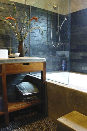 Aménagement d'une salle d'eau moderne en bois brun de taille moyenne avec un placard sans porte, une baignoire en alcôve, un combiné douche/baignoire, WC à poser, un carrelage bleu, des carreaux de porcelaine, un mur bleu, un sol en galet, une vasque et un plan de toilette en stéatite.