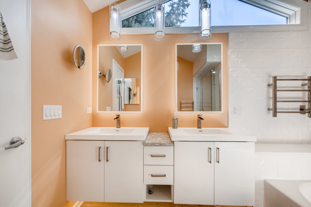 Inredning av ett modernt mellanstort vit vitt en-suite badrum, med släta luckor, vita skåp, ett badkar i en alkov, en hörndusch, grå kakel, marmorkakel, orange väggar, ljust trägolv, ett integrerad handfat, granitbänkskiva, brunt golv och dusch med gångjärnsdörr