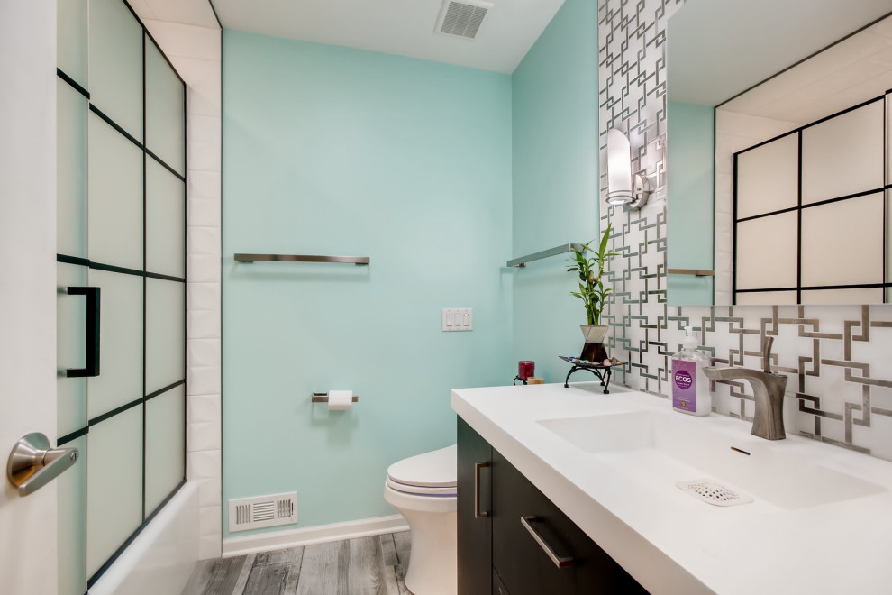 Bild på ett mellanstort vintage vit vitt badrum med dusch, med släta luckor, skåp i mörkt trä, ett badkar i en alkov, en dusch/badkar-kombination, grå kakel, marmorkakel, blå väggar, ljust trägolv, ett integrerad handfat, bänkskiva i akrylsten, grått golv och dusch med gångjärnsdörr