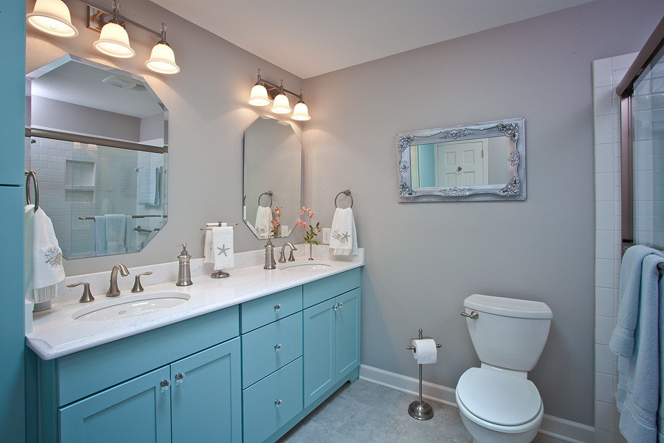 Foto på ett stort maritimt vit badrum med dusch, med ett undermonterad handfat, luckor med infälld panel, blå skåp, bänkskiva i kvartsit, ett badkar i en alkov, en dusch/badkar-kombination, en toalettstol med separat cisternkåpa, vit kakel, keramikplattor, beige väggar, klinkergolv i porslin, grått golv och dusch med skjutdörr