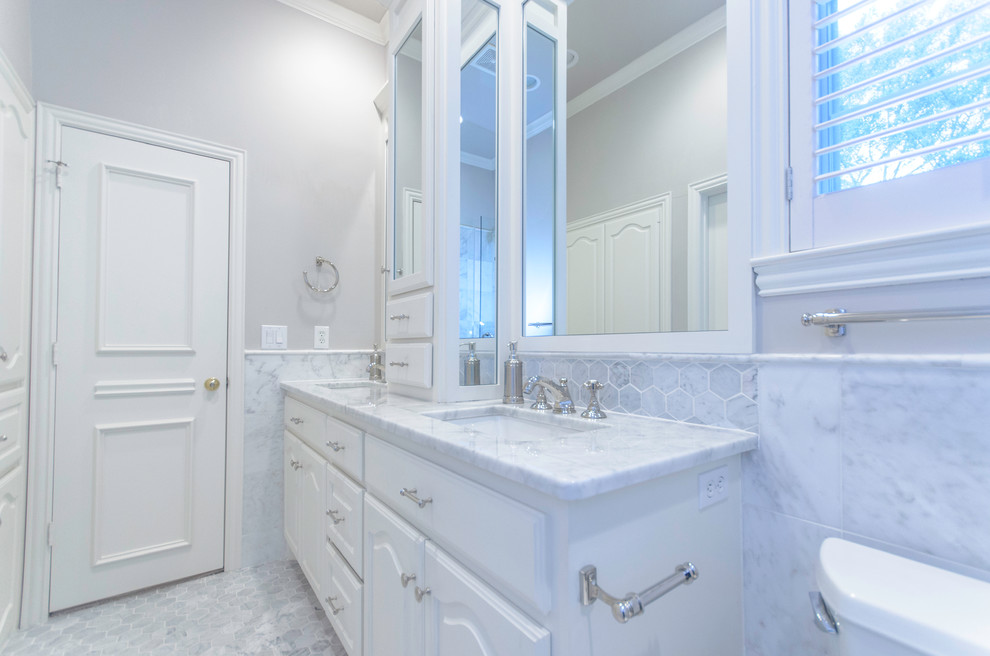 This is an example of a small contemporary bathroom in Dallas with white cabinets, an alcove shower, a one-piece toilet, grey walls, ceramic flooring, raised-panel cabinets, a submerged sink, marble worktops and grey floors.