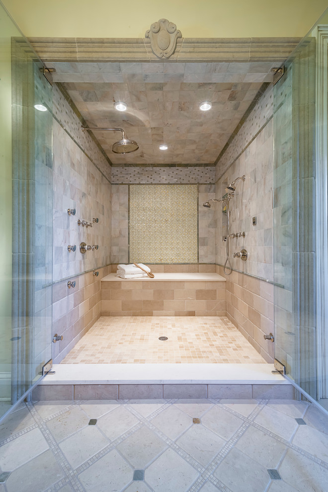 На фото: огромная главная ванная комната с фасадами островного типа, темными деревянными фасадами, отдельно стоящей ванной, двойным душем, бежевой плиткой, терракотовой плиткой, бежевыми стенами, полом из травертина и мраморной столешницей с