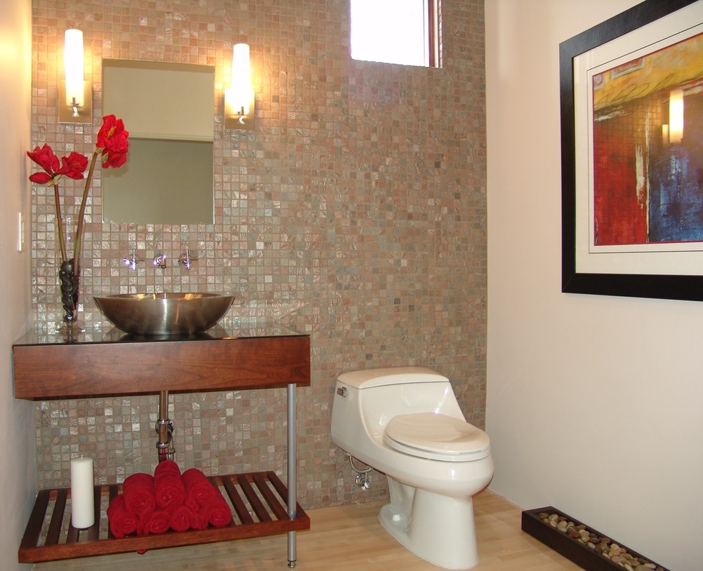 Aménagement d'un petit WC et toilettes éclectique en bois foncé avec WC à poser, mosaïque, un mur blanc, parquet clair, une vasque, un plan de toilette en verre et un sol marron.
