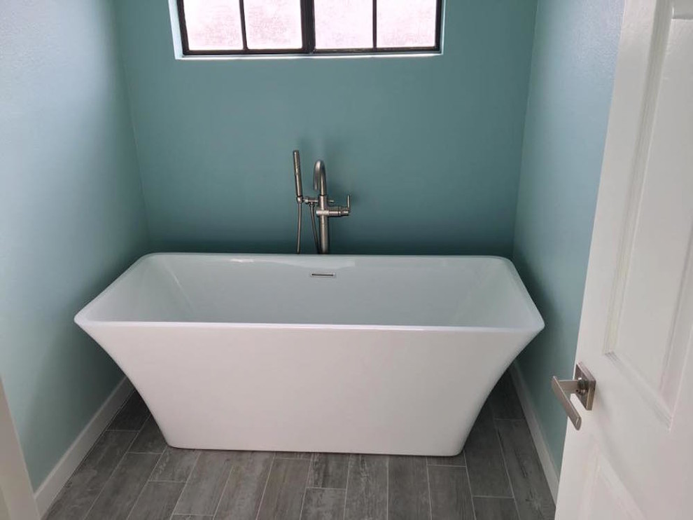 Inredning av ett modernt litet en-suite badrum, med ett fristående badkar, blå väggar, mörkt trägolv och brunt golv