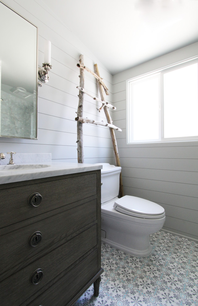 Пример оригинального дизайна: маленькая ванная комната в морском стиле с фасадами островного типа, фасадами цвета дерева среднего тона, душем в нише, раздельным унитазом, серой плиткой, галечной плиткой, серыми стенами, мраморным полом, душевой кабиной, врезной раковиной, мраморной столешницей, разноцветным полом, душем с распашными дверями, белой столешницей, сиденьем для душа, тумбой под одну раковину, напольной тумбой и стенами из вагонки для на участке и в саду
