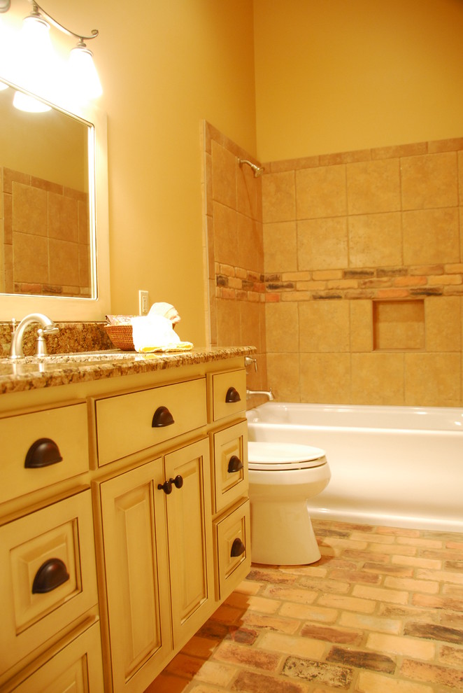 На фото: ванная комната среднего размера в классическом стиле с фасадами с выступающей филенкой, белыми фасадами, ванной в нише, душем над ванной, раздельным унитазом, бежевой плиткой, керамической плиткой, бежевыми стенами, кирпичным полом, душевой кабиной, столешницей из гранита, разноцветным полом и шторкой для ванной
