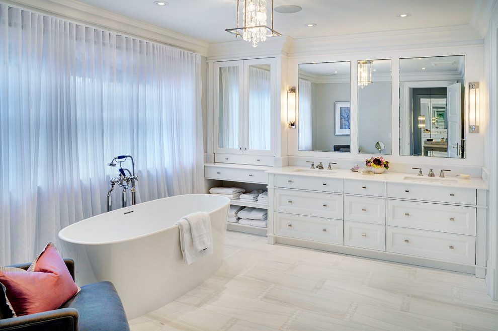 На фото: ванная комната в современном стиле с белыми фасадами и отдельно стоящей ванной с