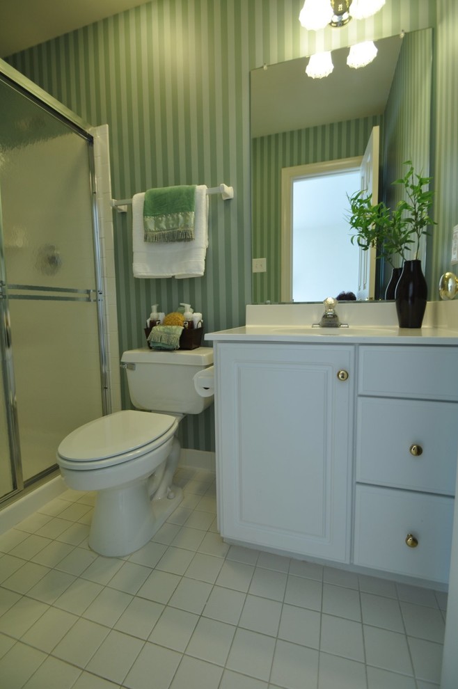 Inspiration för mellanstora klassiska badrum med dusch, med en toalettstol med separat cisternkåpa, gröna väggar, klinkergolv i keramik, luckor med upphöjd panel, vita skåp, en dusch i en alkov, keramikplattor, ett integrerad handfat och bänkskiva i akrylsten