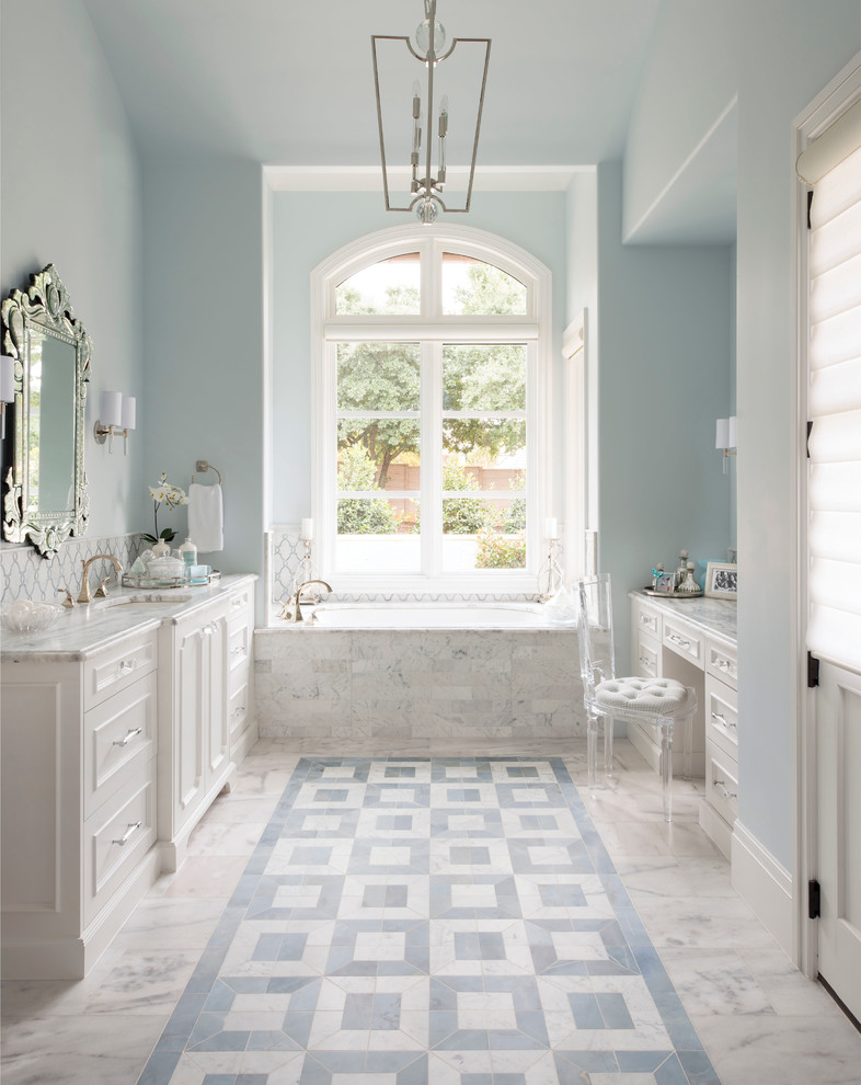 Aménagement d'une salle de bain classique avec un placard avec porte à panneau encastré, des portes de placard blanches, une baignoire en alcôve, un mur bleu, un lavabo encastré et un sol blanc.