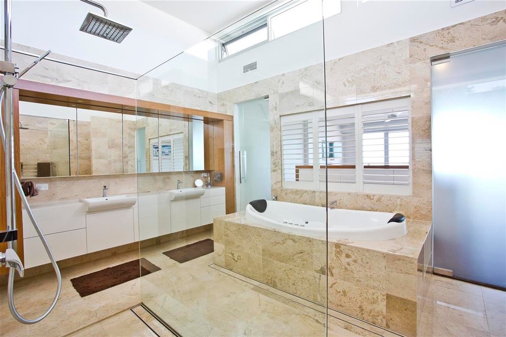 На фото: большая главная ванная комната в современном стиле с плоскими фасадами, белыми фасадами, отдельно стоящей ванной, открытым душем, бежевой плиткой, мраморной плиткой, мраморным полом, раковиной с несколькими смесителями, столешницей из гранита, бежевым полом и открытым душем