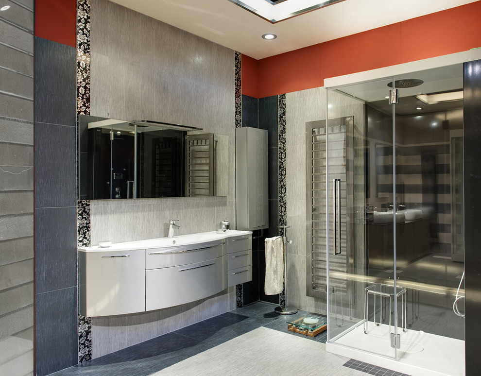 Example of a large minimalist master glass sheet marble floor and gray floor corner shower design in Orange County with flat-panel cabinets, beige walls, an undermount sink, solid surface countertops, white cabinets and a hinged shower door