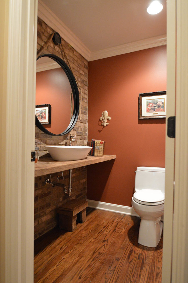 Diseño de cuarto de baño rústico pequeño con sanitario de una pieza, parades naranjas, suelo de madera en tonos medios, encimera de madera y lavabo sobreencimera