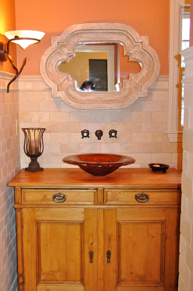 Ispirazione per una piccola stanza da bagno tradizionale con ante a filo, ante in legno chiaro, piastrelle in pietra, pareti arancioni, lavabo a bacinella e top in legno