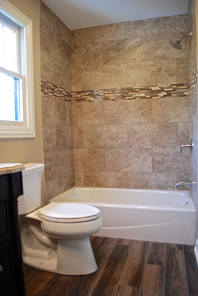 Photo of a small traditional bathroom in Chicago with dark wood cabinets, an alcove bath, a shower/bath combination, a two-piece toilet, brown tiles, porcelain tiles, beige walls, porcelain flooring, a submerged sink and marble worktops.
