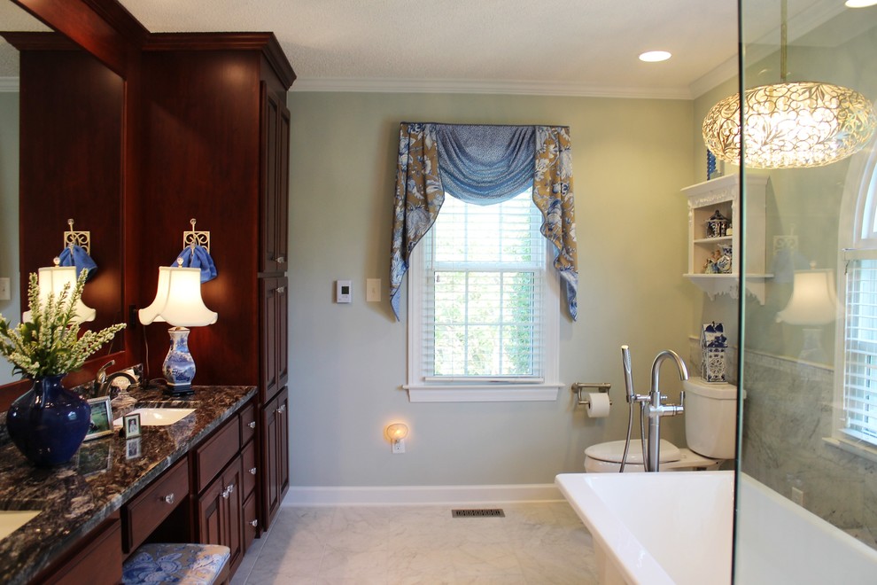 Design ideas for a medium sized traditional ensuite bathroom in Raleigh with raised-panel cabinets, medium wood cabinets, a freestanding bath, a corner shower, a one-piece toilet, white tiles, stone tiles, green walls, marble flooring, a submerged sink and granite worktops.