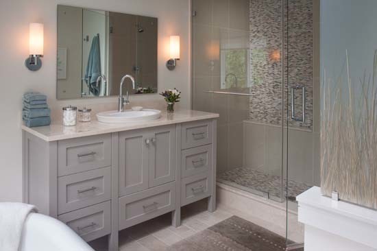 Inredning av ett klassiskt badrum, med ett nedsänkt handfat, möbel-liknande, grå skåp, marmorbänkskiva, ett undermonterat badkar, en dubbeldusch, en toalettstol med separat cisternkåpa och beige kakel