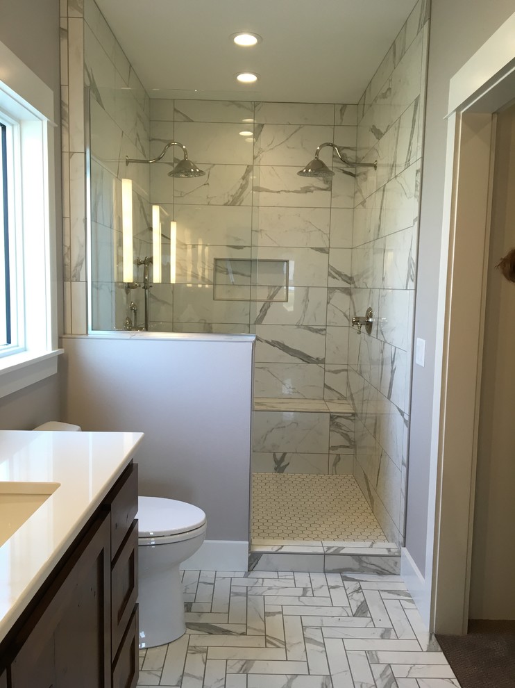 Cette photo montre une salle de bain chic de taille moyenne avec un placard à porte shaker, des portes de placard grises, un carrelage gris, un carrelage blanc, des carreaux de porcelaine, un mur gris, un sol en galet, une vasque et un plan de toilette en stratifié.